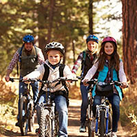 three individuals smiling, on their cycles wearing helmets