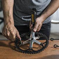 a person fixing a part of a cycle with the pedal attached to it