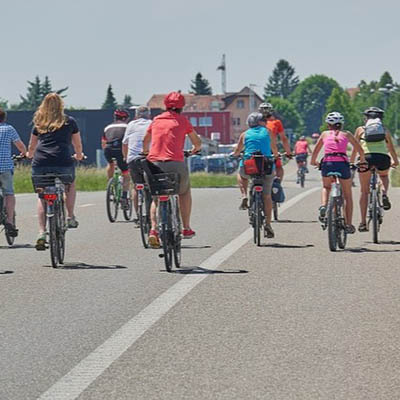 a group of local citizens doing some cycling in the middle of the roads with their backs facing us
