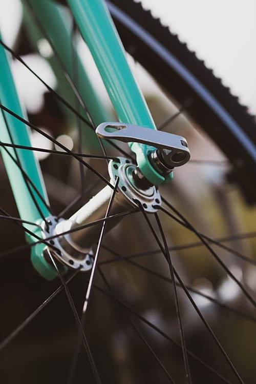 close up of bicycle spokes of a teal-coloured bicycle